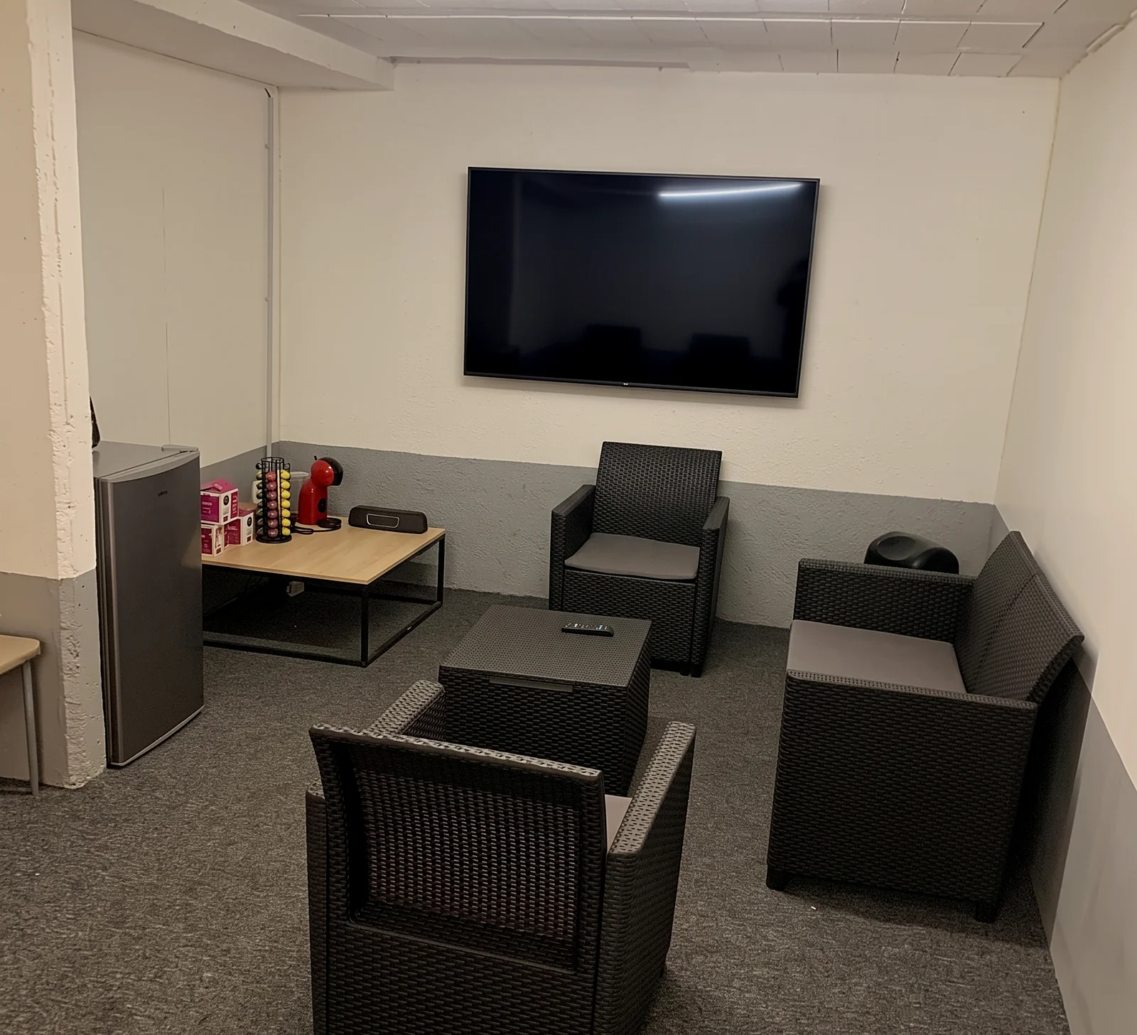 La salle d'attente : fauteuils, écran TV et coin café